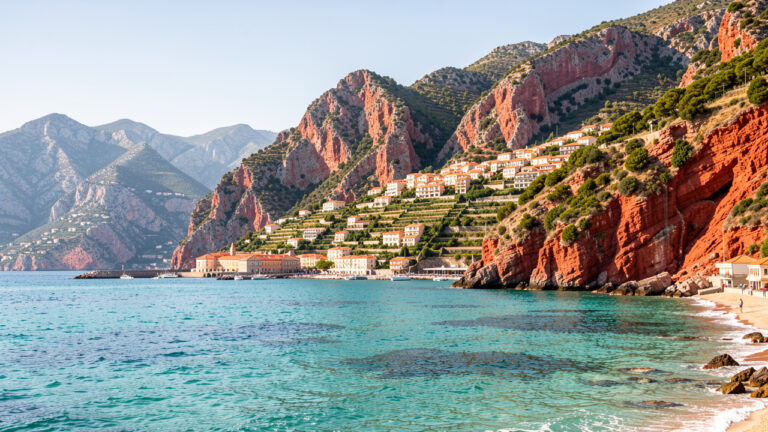 Vue panoramique de Porto en Corse : mer turquoise, falaises rouges, village et montagnes ensoleillés.